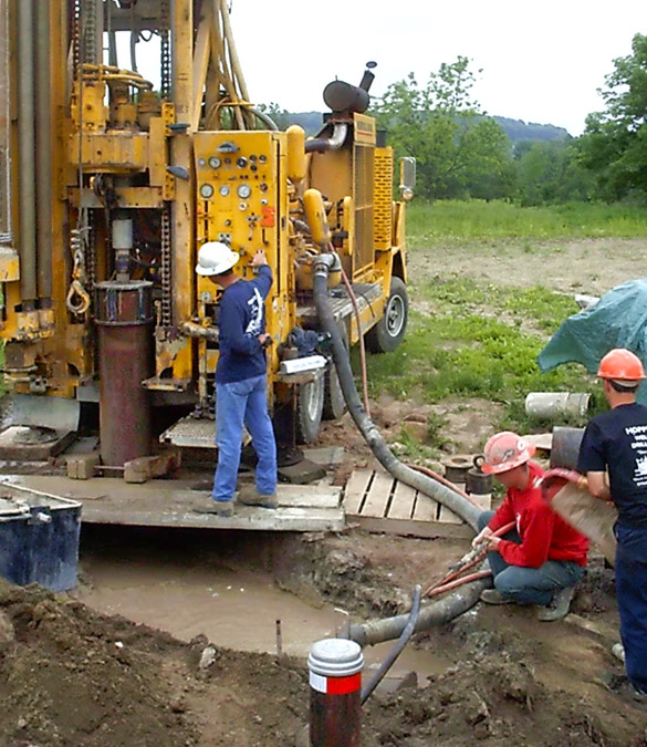 Hopper crew working at a well head alongside the drill rig
